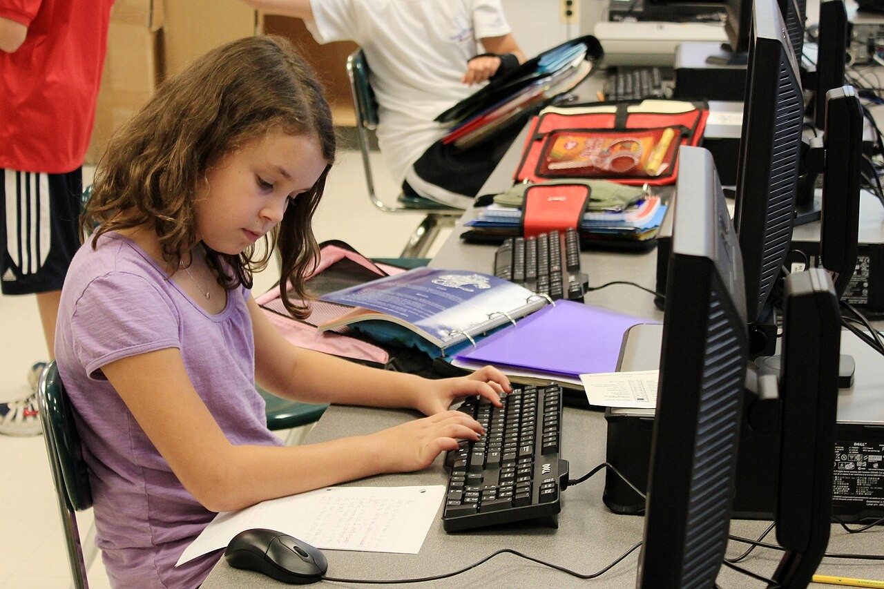 Estudante utiliza computador em atividade escolar.