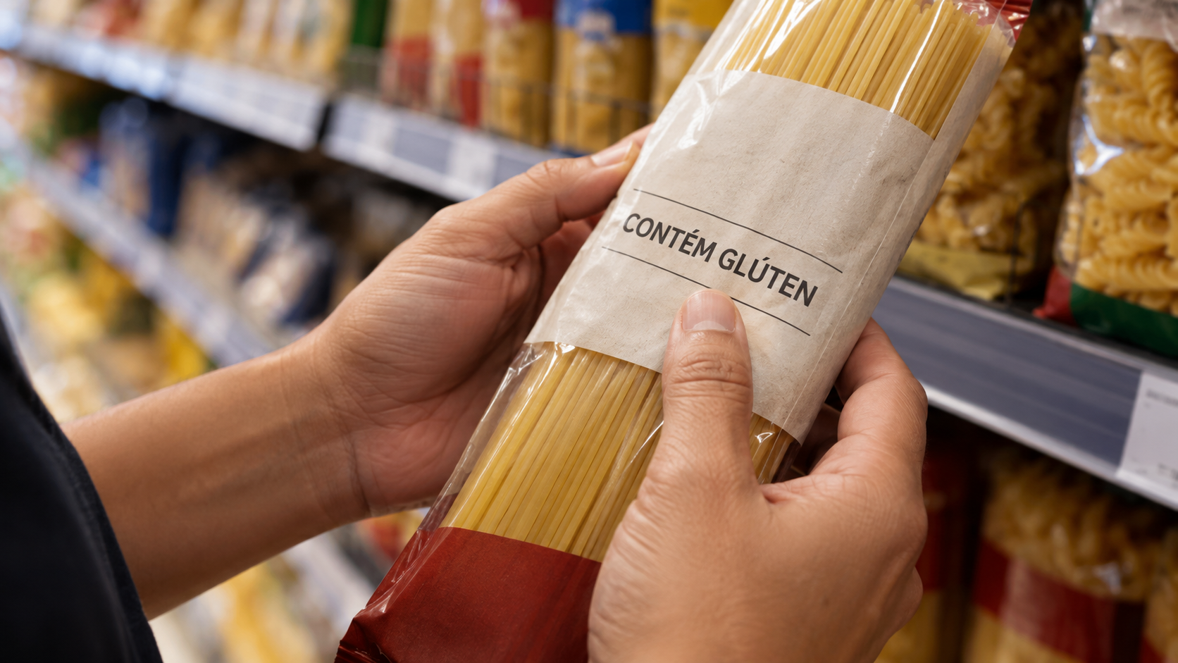 Mãos conferem a advertência de glúten em embalagem ilustrativa de massa alimentícia.