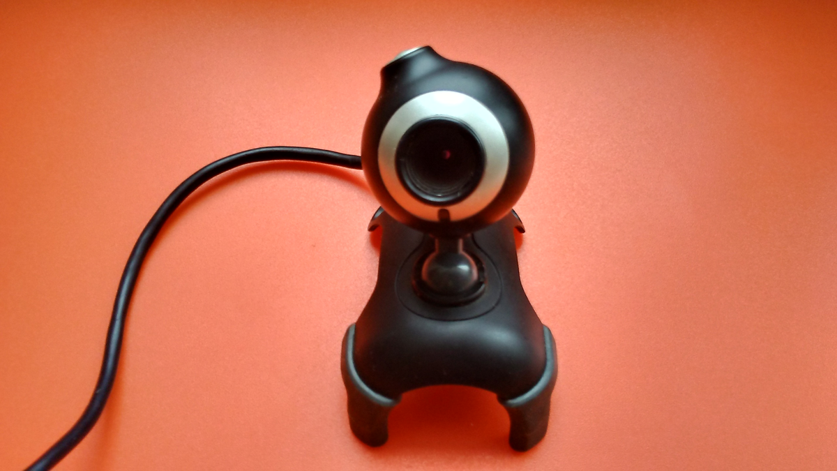 Webcam USB sobre uma superfície vermelha.